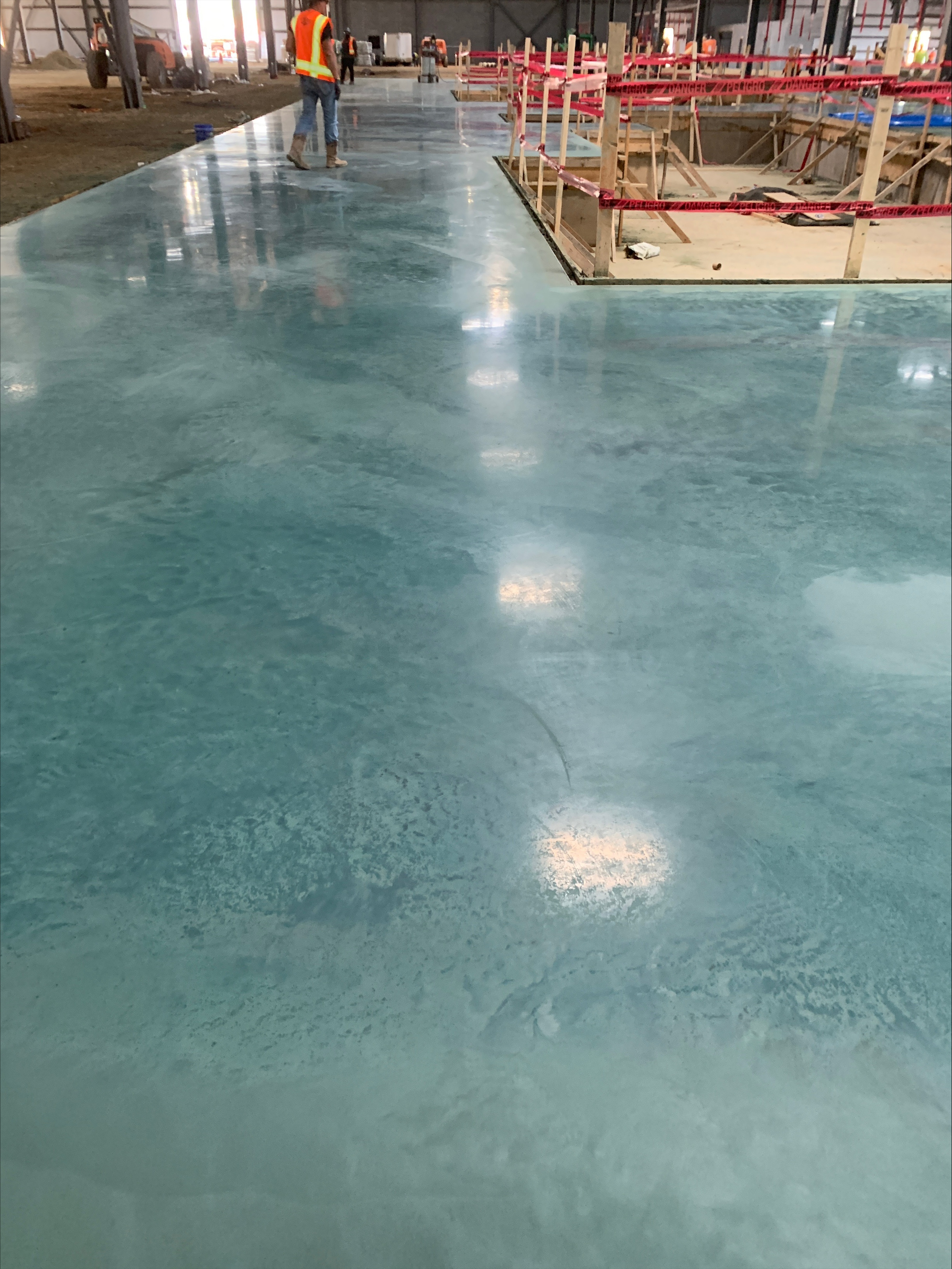 Polished and stained concrete floor with a glossy teal finish inside a warehouse