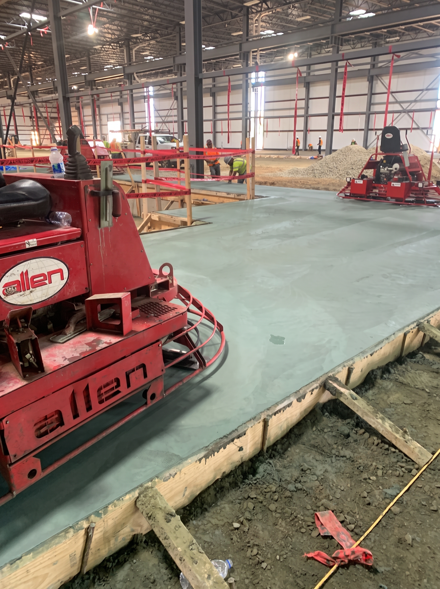 Ride-on power trowel finishing a commercial concrete slab inside a warehouse