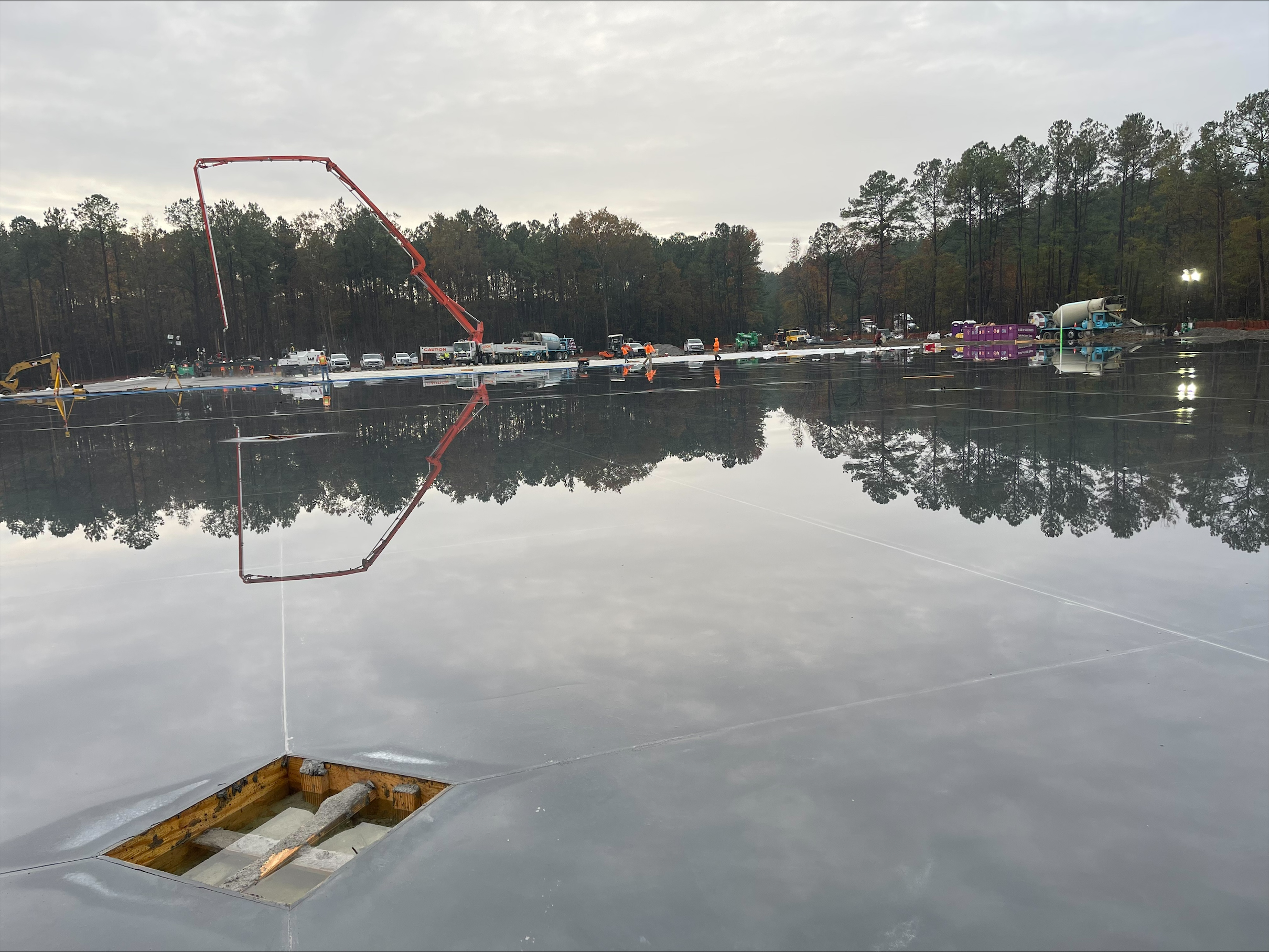 Concrete pump truck arm reflected on a freshly poured commercial slab